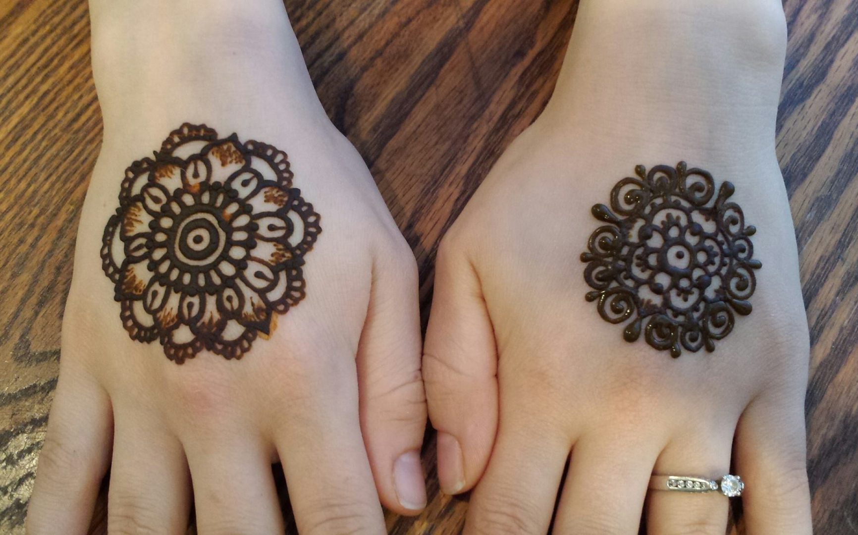 Mandala shaped henna body art on woman's hands.